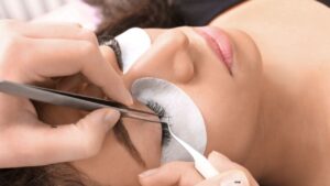 Profissional realizando aplicação de extensão de cílios em cliente durante um Curso de Extensão de Cílios, demonstrando a técnica fio a fio com precisão, higiene e materiais profissionais.